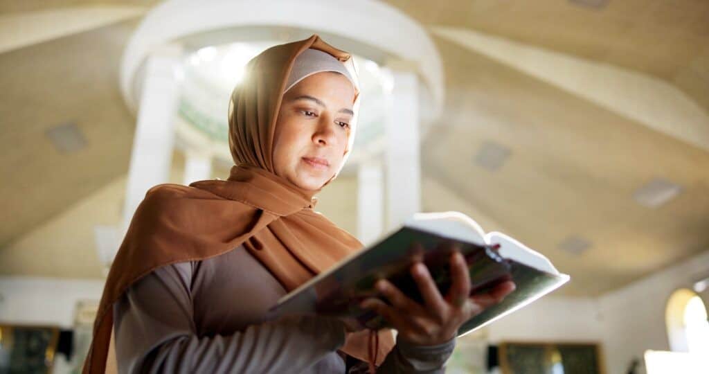 Muslim woman, reading and mosque with quran or holy book for recitation, praying or dua in mosque